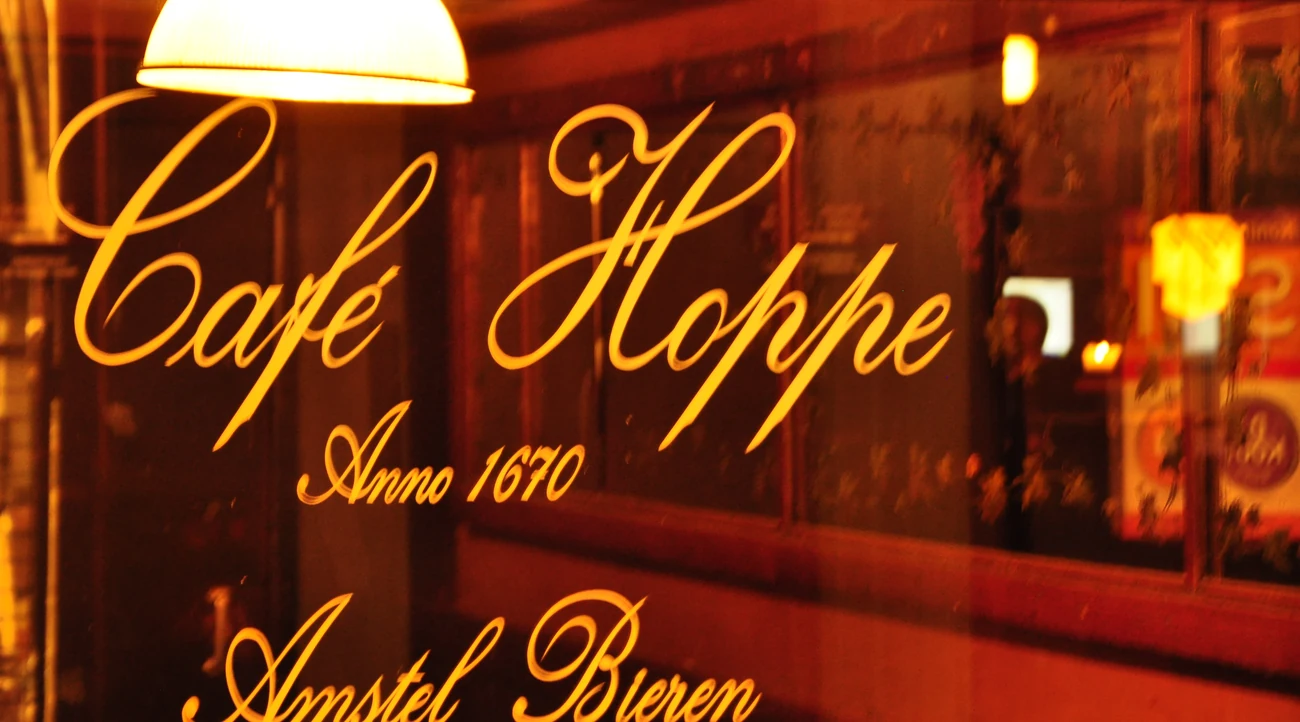 Warmly illuminated Caf&eacute; Hoppe lettering on the window of the historic brown caf&eacute; on Spui in Amsterdam