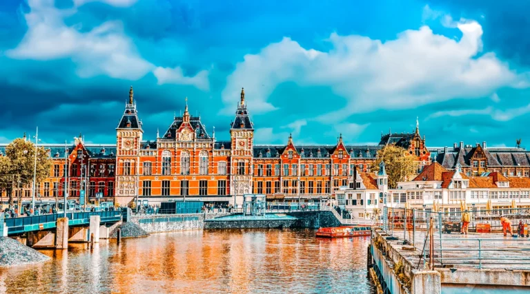 Amsterdam Centraal Station&rsquo;s brick facade and twin towers across the water in daylight