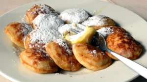 Dutch poffertjes with butter and icing sugar served on a plate at Groot Melkhuis in Amsterdam Vondelpark