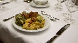 Dutch stamppot made with mashed potatoes and vegetables, served with sausages and bacon on a restaurant table