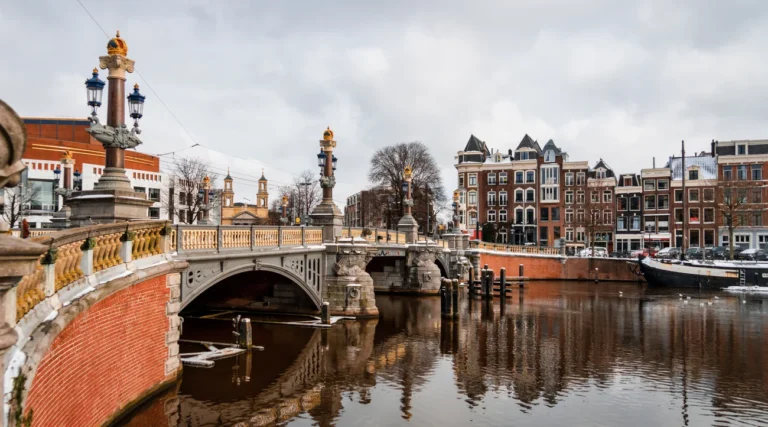 Decorated stone arches, crowned columns and lamps of the Blauwbrug over the Amstel in Amsterdam during daylight