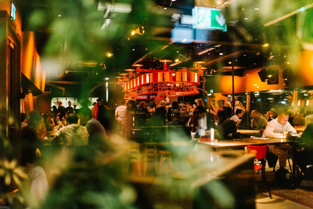 Guests gathered around the illuminated bar inside Canvas at Volkshotel in Amsterdam