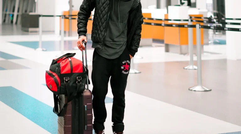 Man standing with luggage in a modern airport terminal, ready for travel.