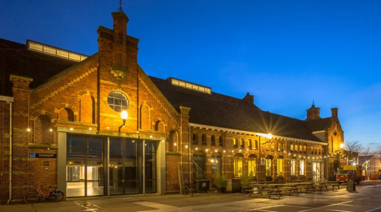 Illuminated historic brick buildings at the Westergas cultural complex in Amsterdam at blue hour
