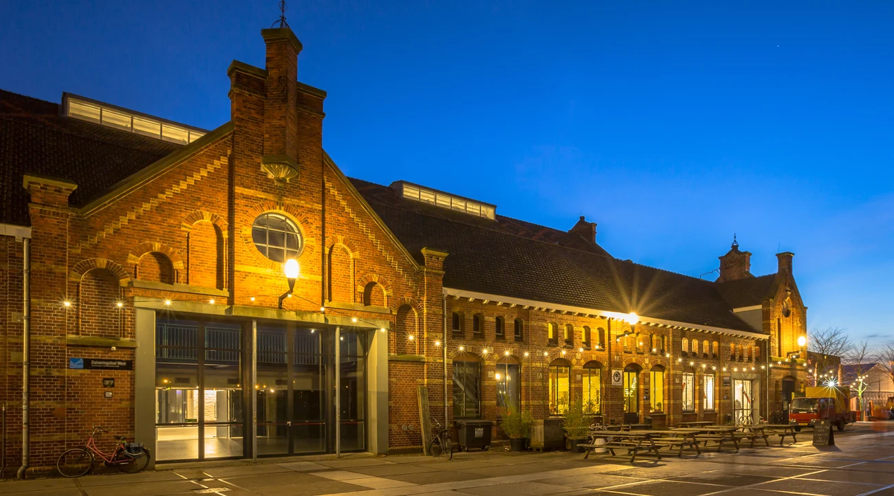 Illuminated historic brick buildings at the Westergas cultural complex in Amsterdam at blue hour