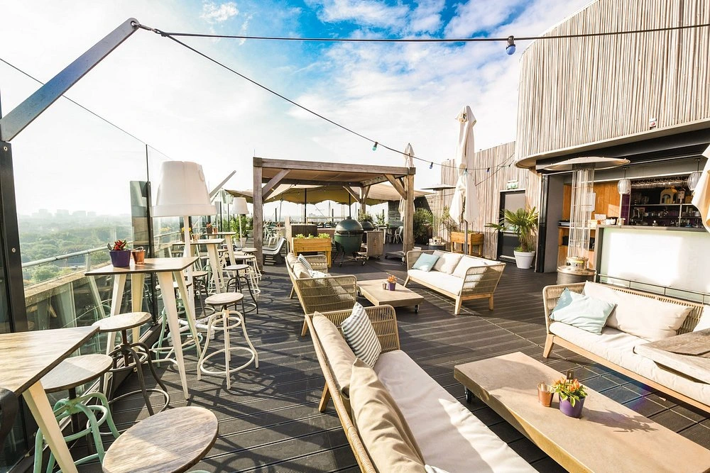 Sunlit rooftop terrace at Floor17 in Amsterdam, with lounge seating, tables and skyline views