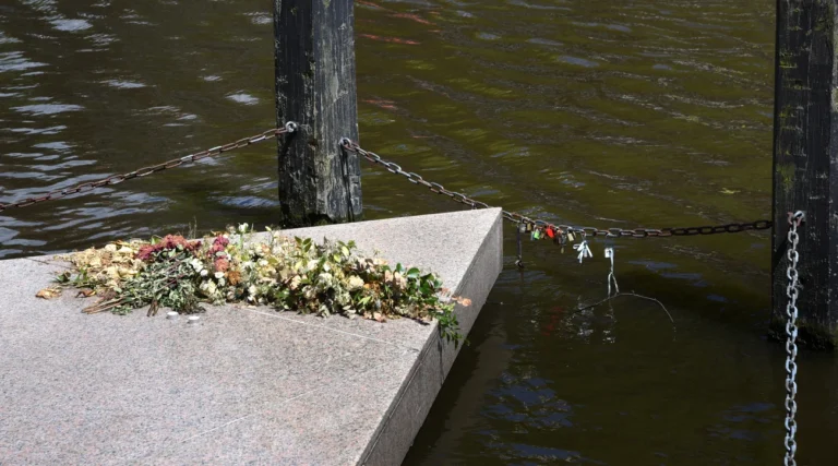 Flowers laid on the pink granite triangle of the Homomonument beside the Keizersgracht canal in Amsterdam in daylight