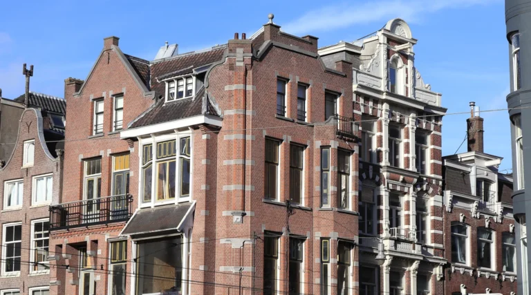 Historic brick facades and gables on Leidsestraat in Amsterdam under a blue daytime sky