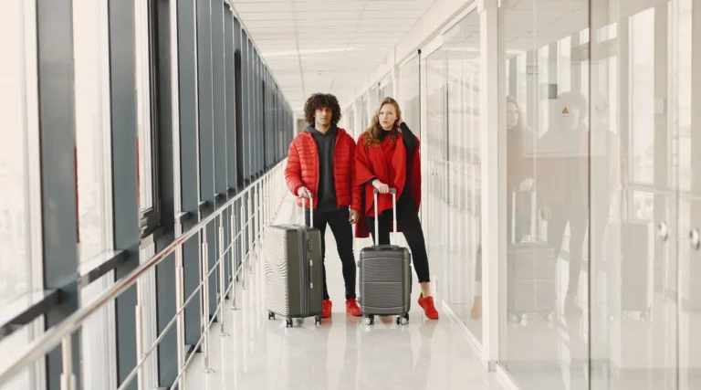 Young couple standing in a hallway with luggage, ready for travel. Bright modern scene.