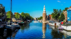Montelbaanstoren tower reflected in the Oudeschans canal in Amsterdam on a sunny day