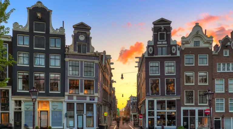 Historic gabled houses framing a street in Amsterdam&rsquo;s Nine Streets area at sunset