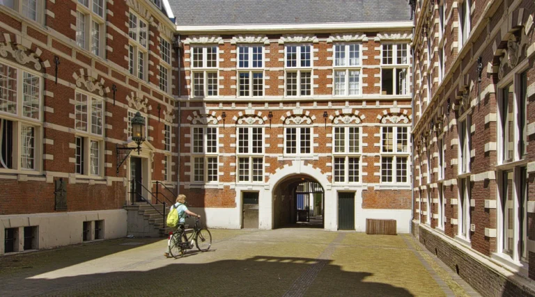 Sunlit brick-and-stone courtyard of Oost-Indisch Huis, the former VOC headquarters in Amsterdam