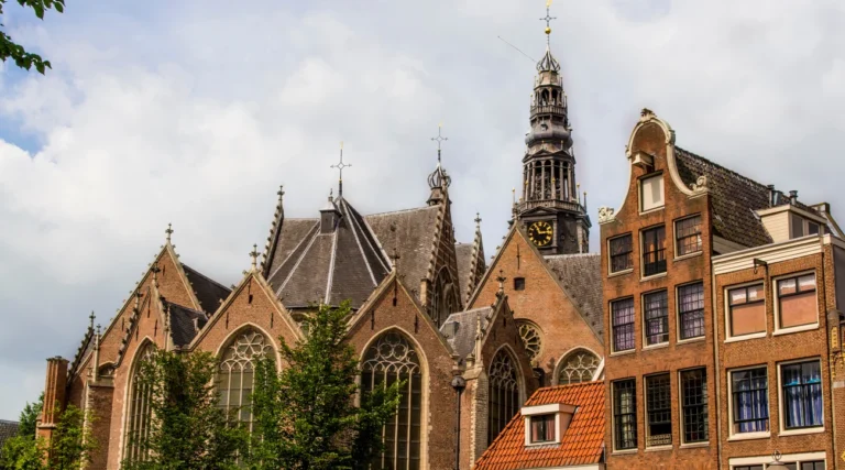Gothic windows, brick gables and clock tower of Oude Kerk in Amsterdam in daylight