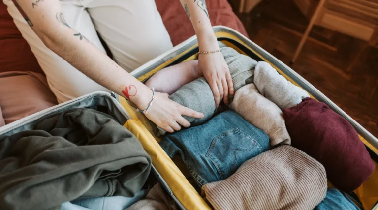 Close-up of a person packing various clothing items into a suitcase, ready for travel.