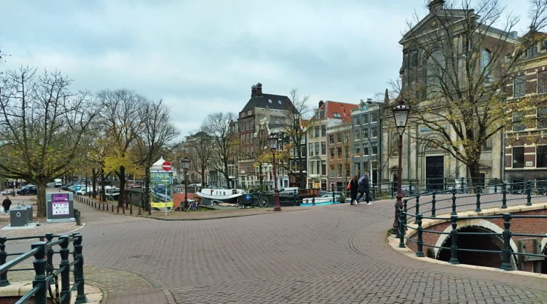 An empty cobblestone canal bridge in Amsterdam with classic Dutch architecture in autumn.