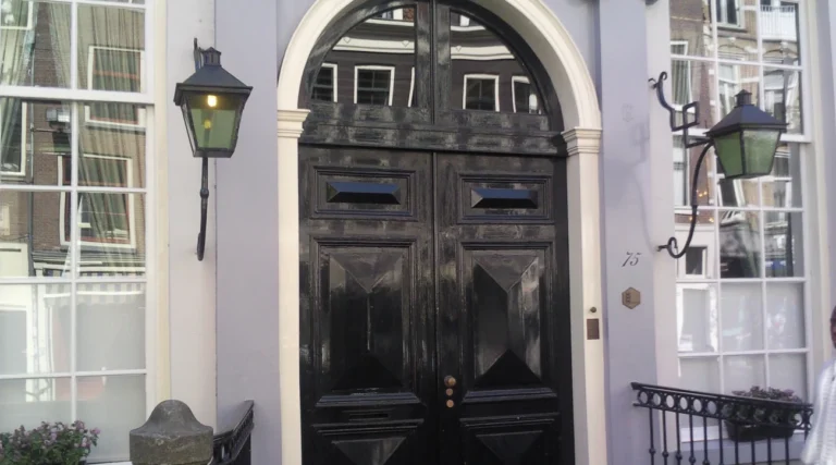 Historic arched doorway of West-Indisch Huis in Amsterdam, with lanterns and tall windows