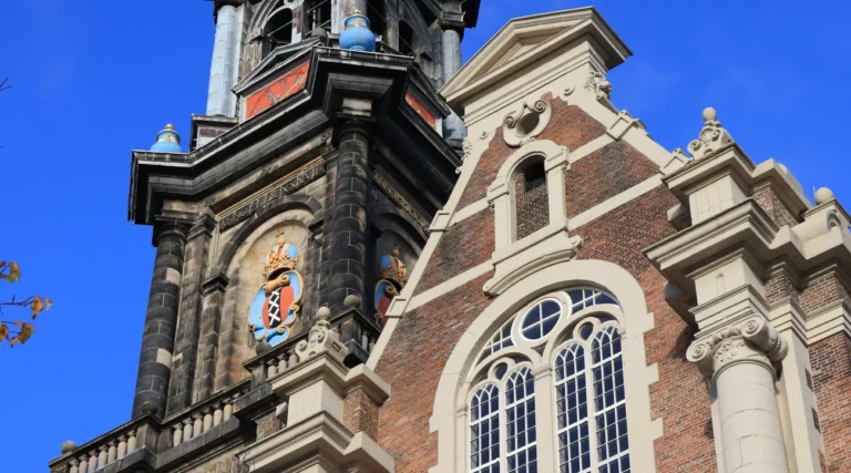 Decorative brickwork, a large window and part of the Westertoren above Westermarkt in Amsterdam in daylight