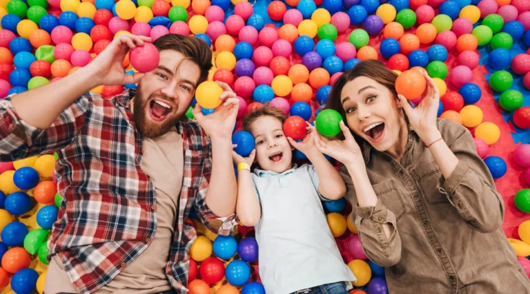 A family smiling among colourful balls in an indoor ball pit