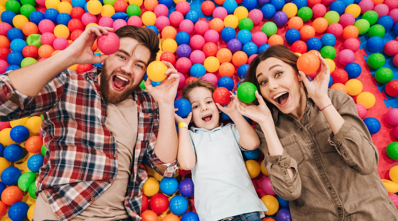 A family smiling among colourful balls in an indoor ball pit