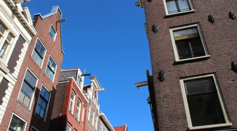 Historic brick fa&ccedil;ades at Zeedijk and Stormsteeg in Amsterdam under a blue sky